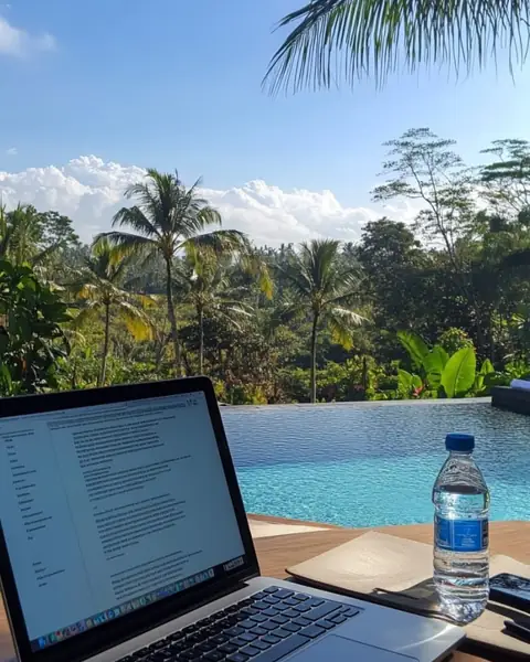 Laptop by an infinity pool in the tropics